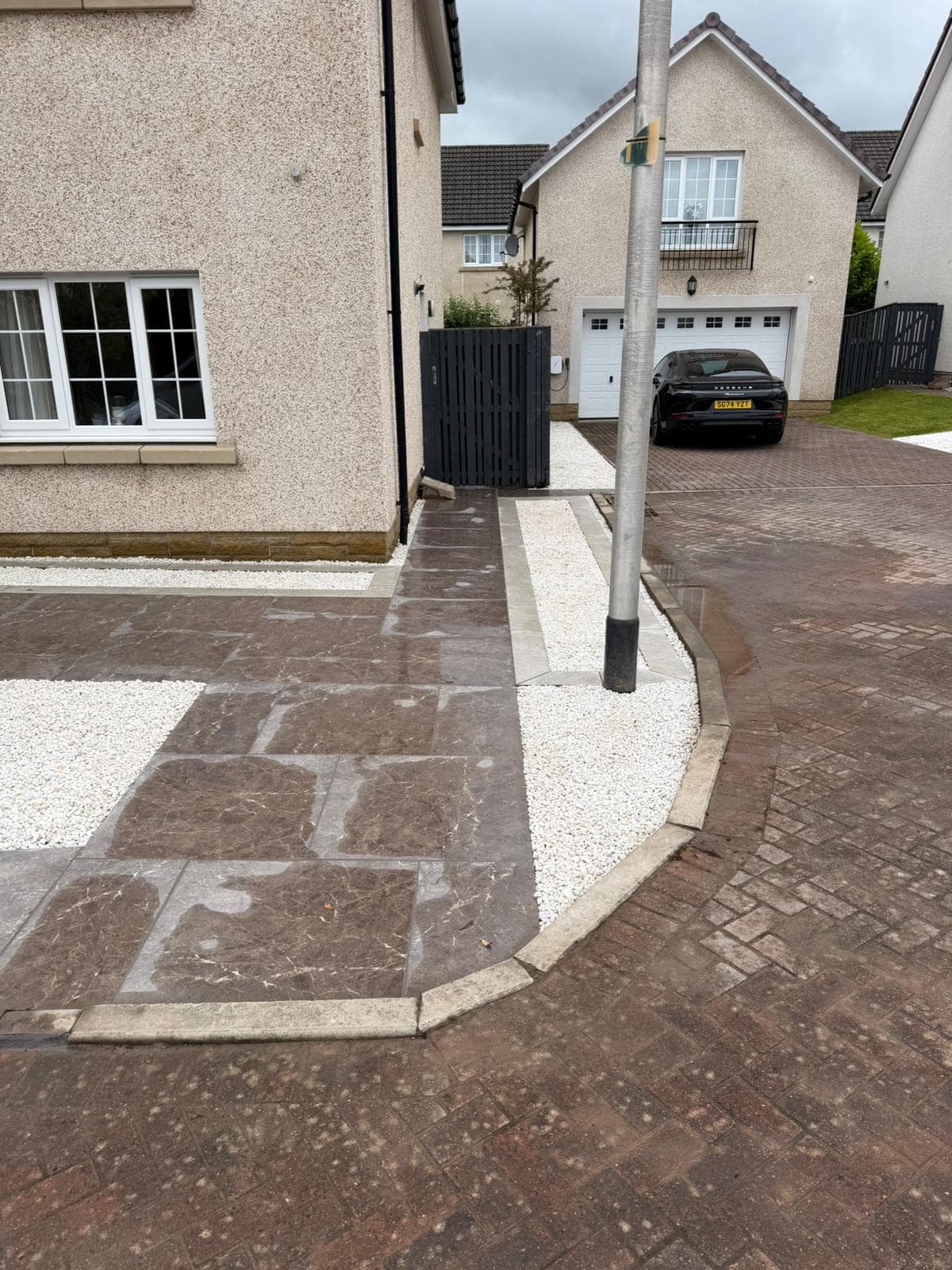 Porcelain path running round the gable to the side gate in Dargavel, with white gravel margins cut neatly around the lamp column and downpipe
