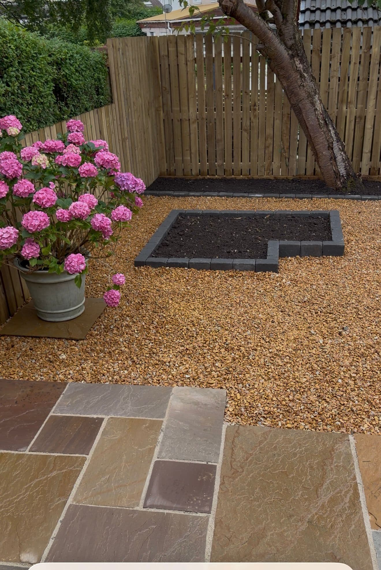 Potted hydrangea beside a raised planting bed and sandstone patio at a Renfrew home