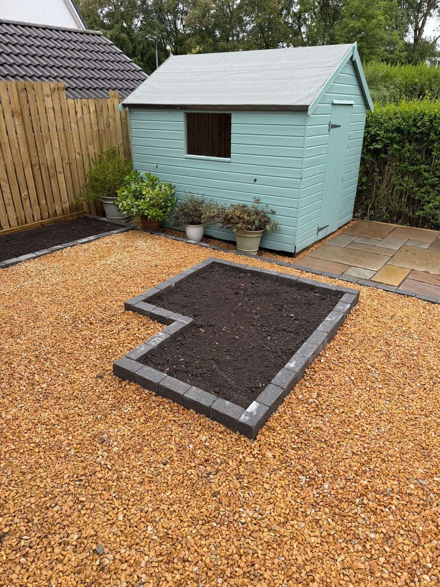 Finished rear garden with sandstone patio, gravel and a garden shed at a village property in Bowling