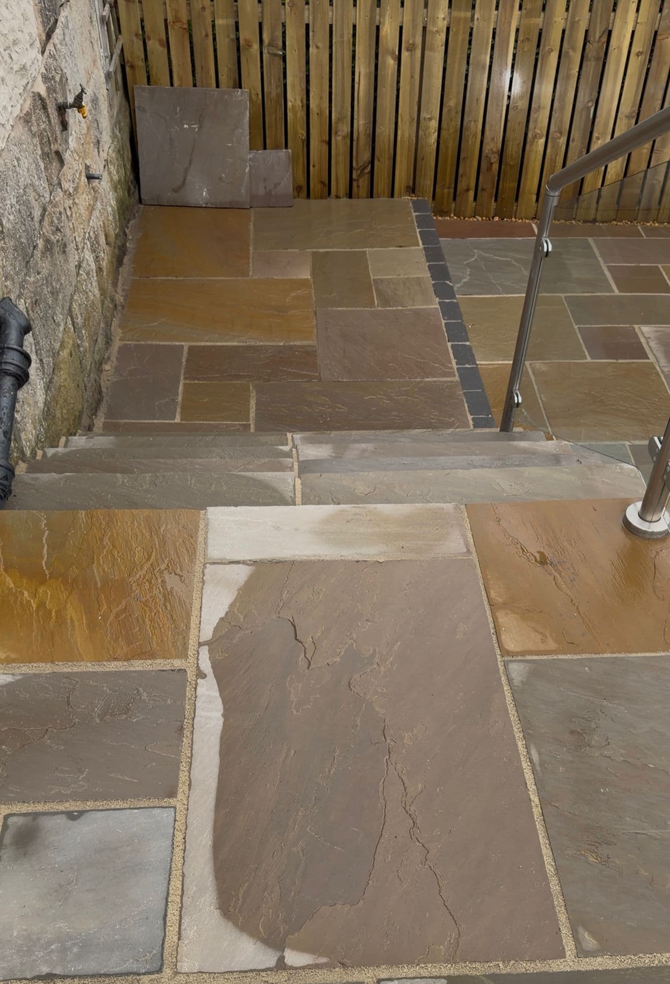 Detail of sandstone patio steps and glass balustrade in a landscaped Erskine garden